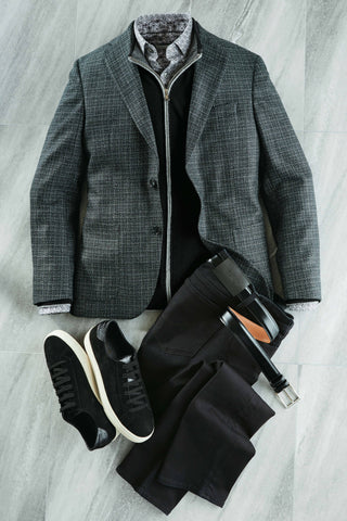 Gray checkered blazer, black pants, black sneakers, and a belt on a light gray surface.