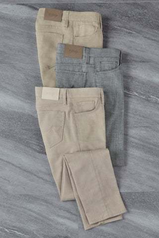 Three pairs of pants in beige and gray on a gray marble surface