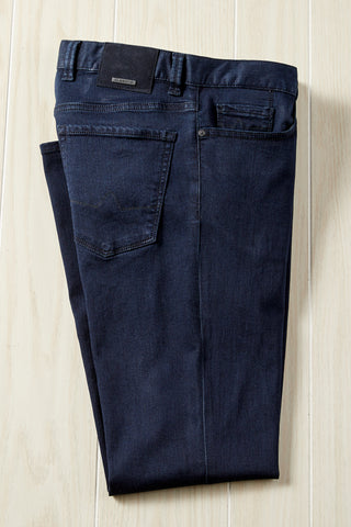 Folded dark blue jeans on a light wooden surface