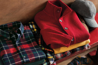 Red sweater, plaid shirt, and cap on a wooden surface - Men's Holiday 2025