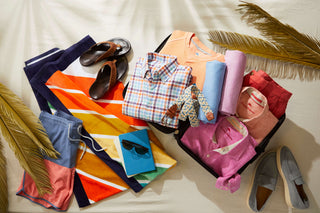 Colorful clothing and accessories arranged on a white surface with palm leaves - summer 2026 - patrick james